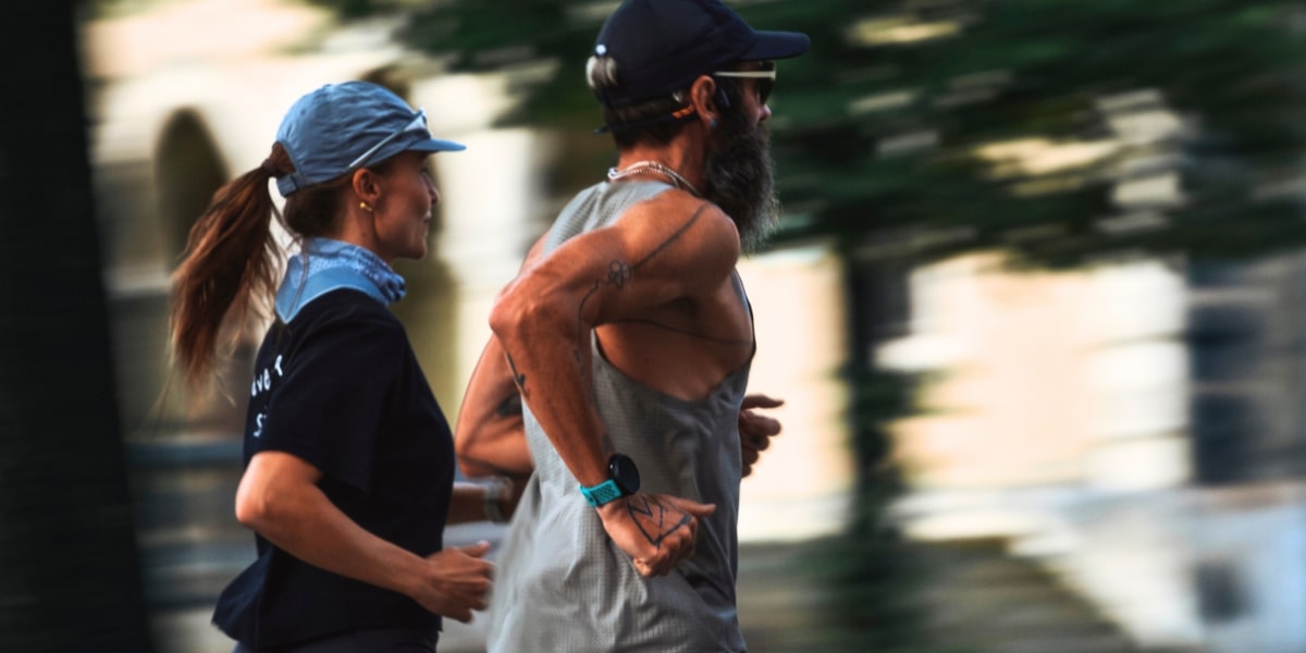 Två löpare tränar utomhus, den ena har en Suunto Race 2 sportklocka på handleden.